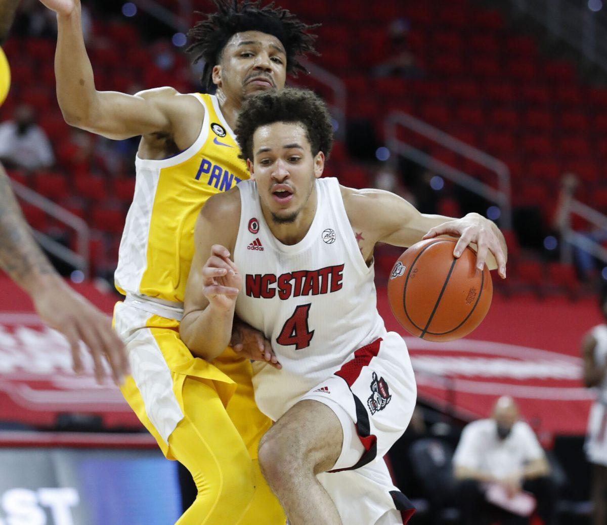 N.C. State's Jericole Hellems (4) drives by Pittsburgh's Ithiel Horton (0) during the first half of N.C. State&#8217;s game against Pittsburgh at PNC Arena in Raleigh, N.C., Sunday, February 28, 2021.