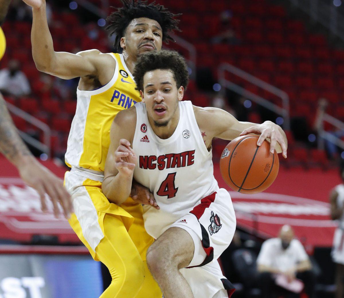 N.C. State's Jericole Hellems (4) drives by Pittsburgh's Ithiel Horton (0) during the first half of N.C. State&#8217;s game against Pittsburgh at PNC Arena in Raleigh, N.C., Sunday, February 28, 2021.