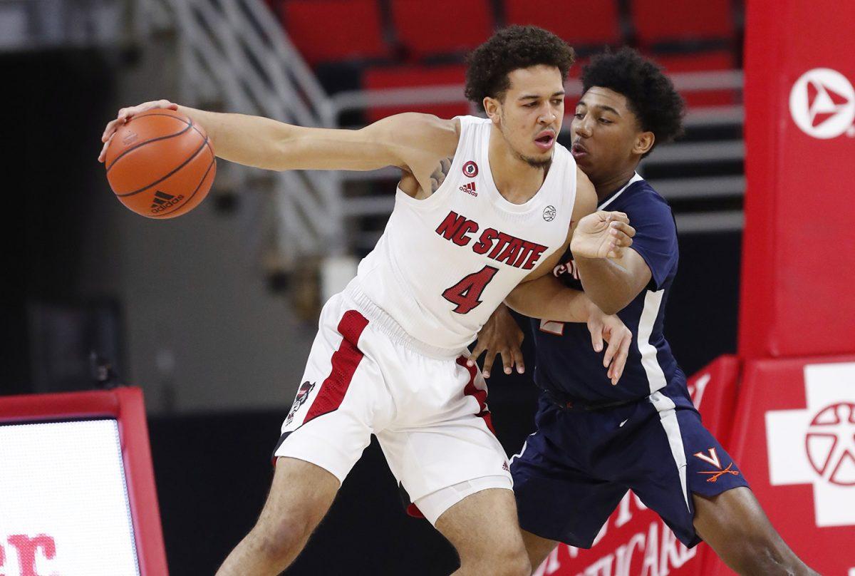 N.C. State's Jericole Hellems (4) looks for room as Virginia's Reece Beekman (2) defends during the first half of N.C. State&#8217;s game against Virginia at PNC Arena in Raleigh, N.C., Wednesday, February 3, 2021.