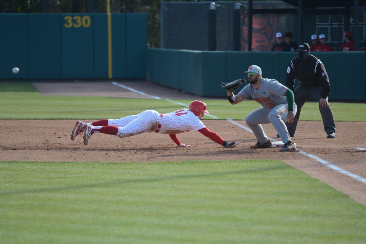 Junior outfielder Jonny Butler dives back to first base after a pickoff attempt at Doak Field on Friday, March 5, 2021. Butler had 2 hits and 1 run scored in the Wolfpack&#8217;s 11-5 win over the Miami Hurricanes.