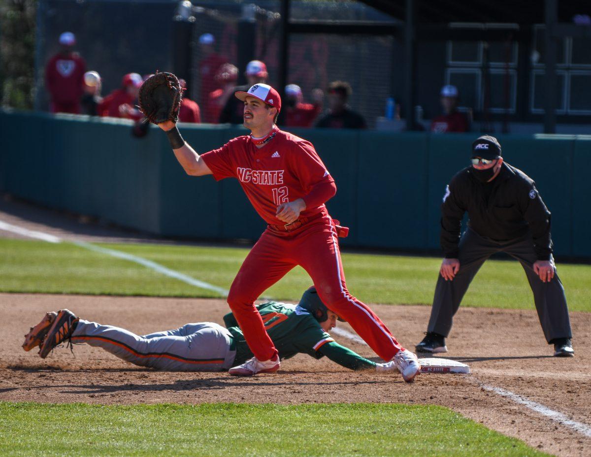 Junior infielder Austin Murr waits for the ball as a runner slides back to first base during the game versus the Miami Hurricanes on Sunday, March 7, 2021 in Doak Field at Dail Park. The Hurricanes beat the Wolfpack 6-4.