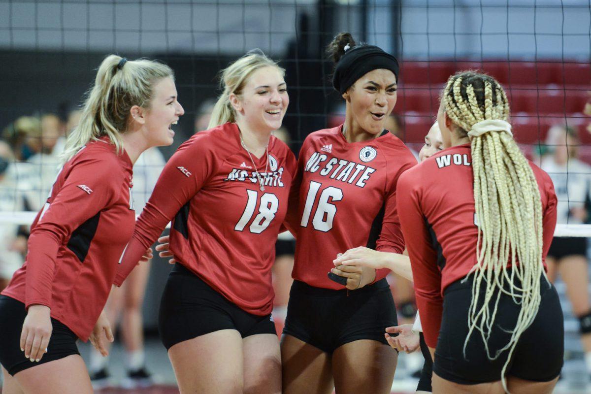 The NC State Wolfpack players, from left, redshirt junior Taylor Rowland (12), freshman Oliwia Durka (18), freshman Jada Allen (16), and graduate student Melissa Evans (3), celebrate scoraing a point against the Coastal Carolina Chanticleers in the first exhibition match of the season in Reynolds Coliseum on Saturday, August 21, 2021. The Chanticleers won the match 3-1.