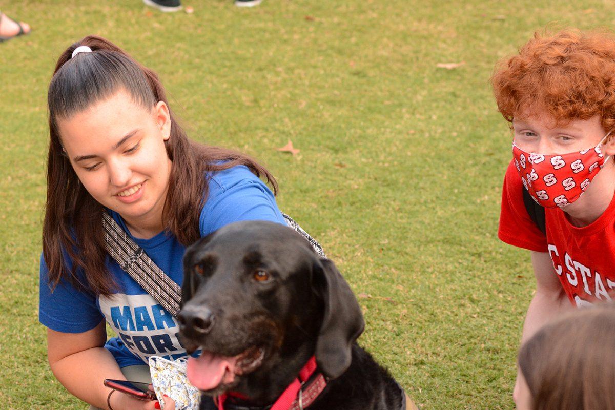 Rebecca Williams, a first-year applied math student and Jacob Lanier, a first-year conservation biology student plays with dog Forest at the Pause for Paws event on Thursday, Sept. 30, 2021 at Harris Field.