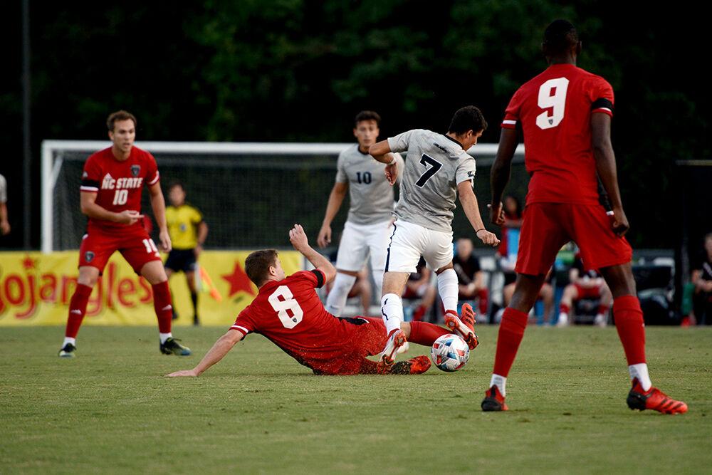 Graduate student midfielder Brad Sweeny slide tackles UCF junior foward Gino Vivi for possession of the ball on Monday, Sep. 6, 2021 at Dail Soccer Stadium. NC State beat UCF 2-1