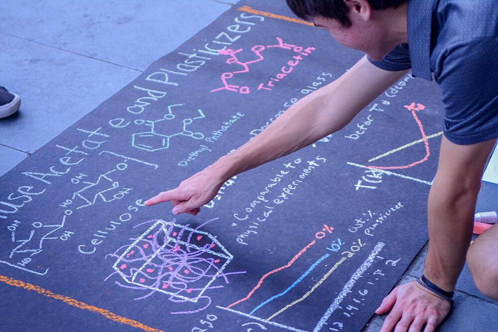 Jason Rhodes, a fourth-year majoring in paper science engineering, points at the molecular structure of cellulose on Sept. 30, 2021 at the Sidewalk Symposium outside of D.H. Hill Library. He partnered with Tom Zarszynski, a second-year majoring in chemical engineering, on this project.