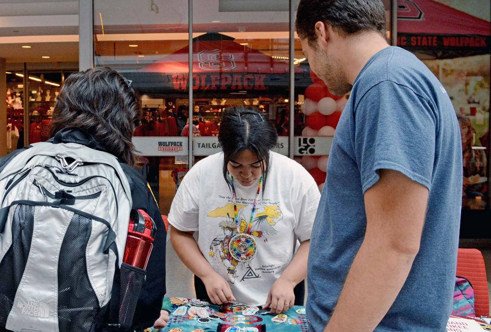 Amberlina Alston, a third-year studying psychology; Belton Moore, a second-year studying economic and political science, and Carmen Palacios-Aguirre, a second-year studying sociology, browse Native American jewelry handcrafted by Alston at the Talley Student Union lobby on Wednesday. Alston, a Lumbee, is the historian of the Native American Student Association, which hosted an event showcasing the history and culture of the various Native American tribes in North Carolina to kickoff Native American Heritage Month.