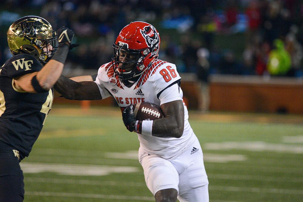 Senior receiver Emeka Emezie stiff-arms a defender during NC State's game against Wake Forest on Saturday, Nov. 13, 2021 at Truist Field in Winston-Salem. The Wolfpack lost to the Demon Deacons 45-42.