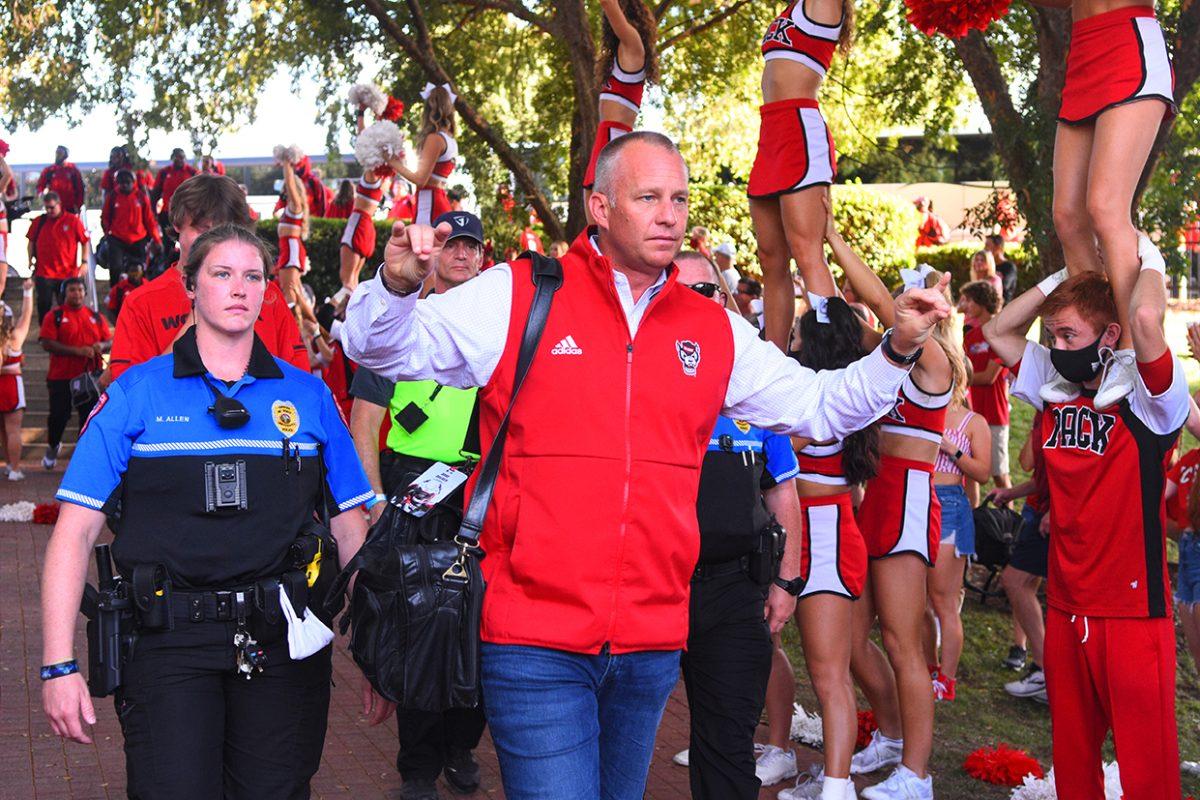 NCSU football coach Dave Doeren holds up his "wolfies" during the Walk of Champions before the game against Furman on Saturday, Sept. 18 outside of Carter-Finley Stadium.