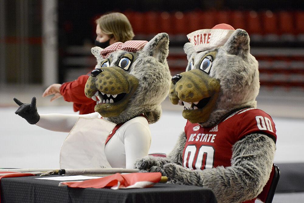 Mr. and Mrs. Wuf sit at the judges table at the NC State Red and White Exhibition meet at Reynolds Coliseum on Friday, Dec. 17, 2021. The team competed against each other at the preseason competition and the white team beat the read team 10-7.