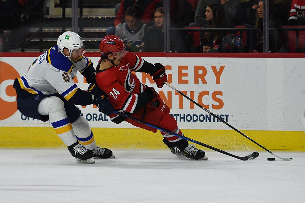 Center Seth Jarvis attempts to take control of the puck while a St. Louis player brings him down in the game in PNC Arena on Saturday, Nov. 13, 2021. The Hurricanes won 3-2.