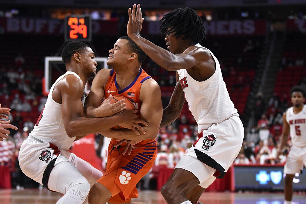 Junior guard Casey Morsell goes for the ball while redshirt sophomore guard Dereon Seabron blocks the Clemson player during the game on Saturday, Jan. 8, 2022 in PNC Arena. NC State lost 70-65.