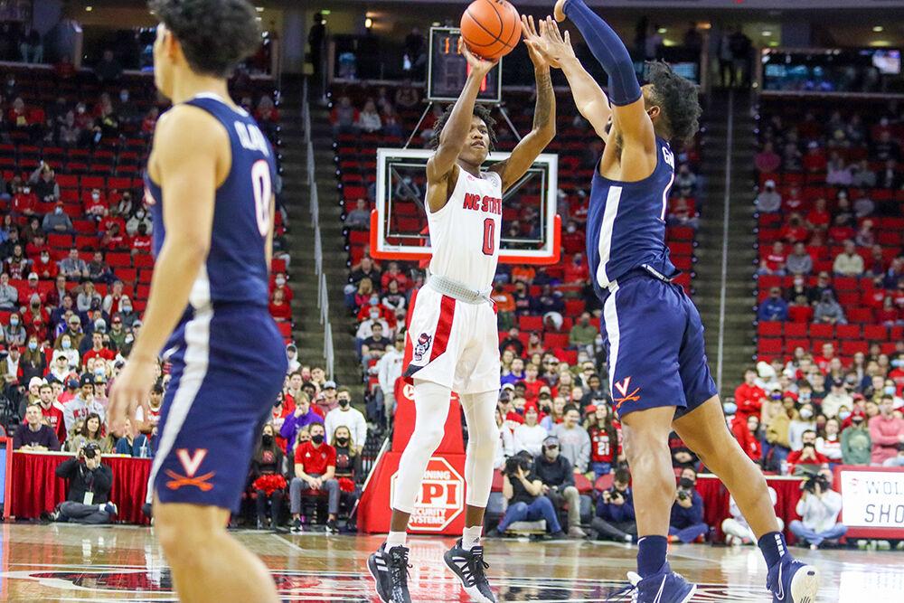 Freshman guard Terquavion Smith shoots a three-pointer against a Virginia defender in the men's basketball home game against Virginia at PNC Arena on January 22, 2022. Smith contributed 20 points and three assists. NC State beat Virginia 77-63.&#160;
