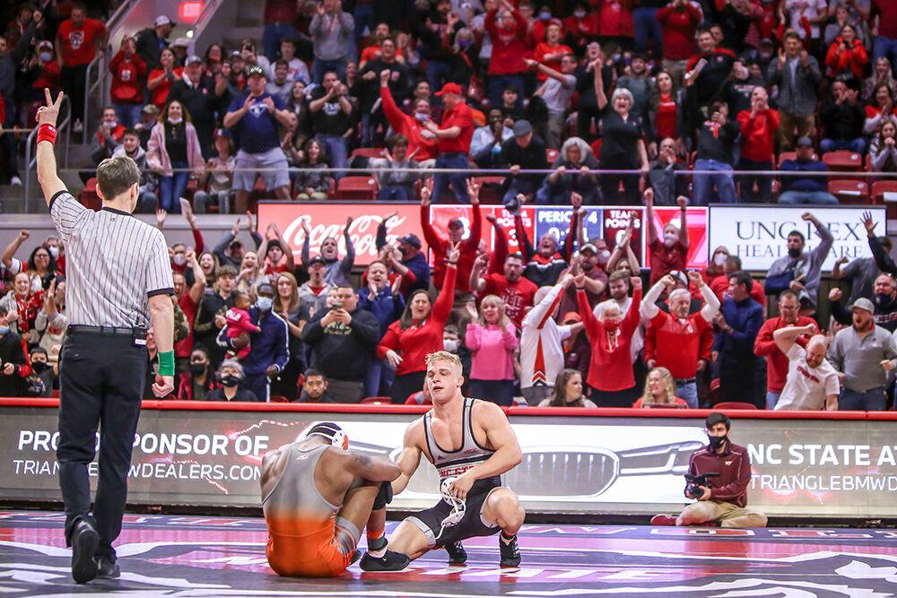NC State graduate student Hayden Hidlay looks down at Virginia Tech's Mekhi Lewis as the crowd cheers his overtime takedown to win their match 3-1. NC State beat Virginia Tech 21-10 in a wrestling match in Reynolds Coliseum on Sunday, Feb. 20, 2022.