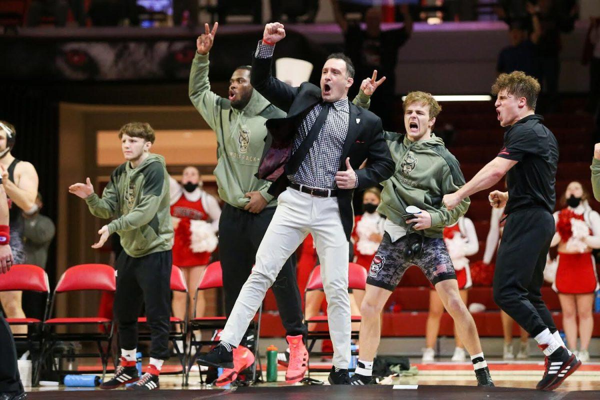 Head coach Pat Popolizio celebrates a last minute takedown giving freshman Isaac Trumble, No. 20 in the 197 weight class a win over No. 13 Jay Aiello. The Wolfpack won all but one bout on the way to a 32-2 win over Virginia on Friday, Feb. 4, 2022, in Reynolds Coliseum.