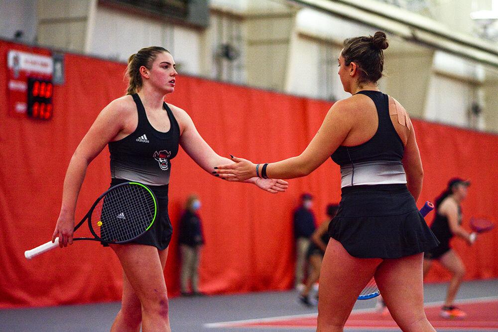 Sophomore tennis player Amelia Rajecki (left) high-fives sophomore Abigail Rencheli (right) during the tennis match against Wake Forest at J.W. Isenhour Tennis Center on Sunday, Jan. 30, 2022. The Wolfpack beat the Demon Deacons 4-0.