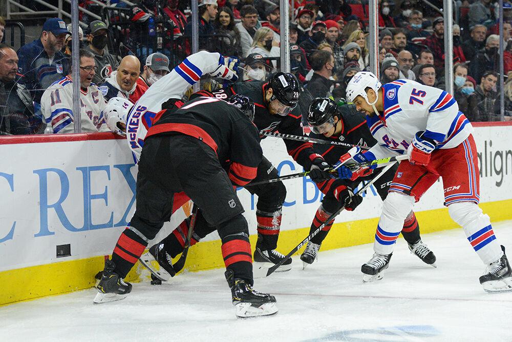 Left defensemen Brendan Smith and Ian Cole and center Seth Jarvis battle for the puck in PNC Arena on Friday, Jan. 21, 2022. The Hurricanes beat the New York Rangers 6-3.