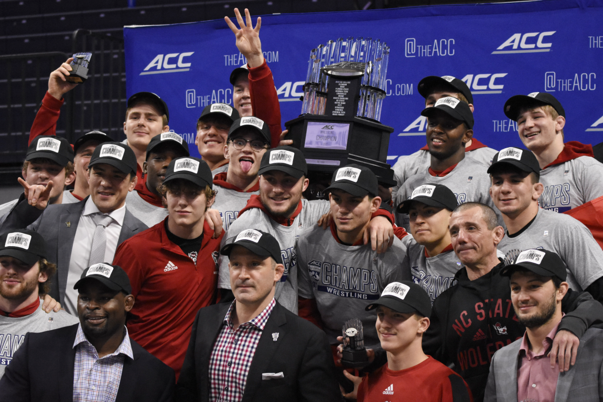 The No. 4 NC State wrestling team celebrates with the ACC Championship trophy after winning the 2022 ACC Championships at John Paul Jones Arena in Charlottesville, Virginia. NC State won the team score with 98.5 total points.