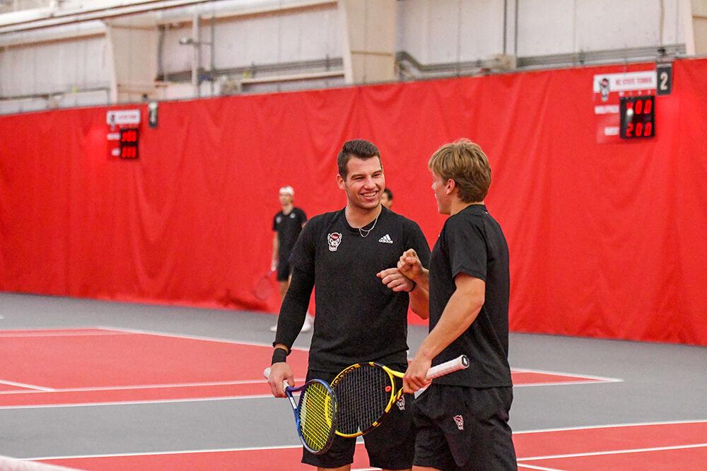 Junior Martins Rocens smiles and fist-bumps freshman Fons Van Sambeek in their doubles match against Boston College on Sunday, Feb. 27, 2022 at J.W. Isenhour Tennis Center. Rocens and Van Sambeek won their match 6-1. The Wolfpack won the overall match against the Eagles 7-0.