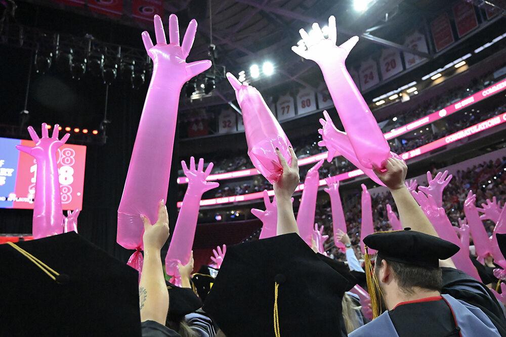 Veterinary medicine graduates wave around palpation gloves in the air at the NC State Commencement in PNC Arena on Saturday, May 7, 2022.