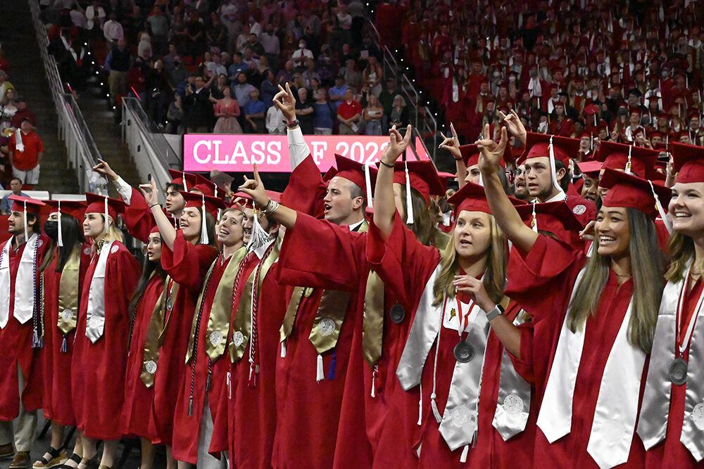 Graduates hold up the Wolfpack symbol during the NC State Commencement ceremony in PNC Arena on Saturday, May 7, 2022.