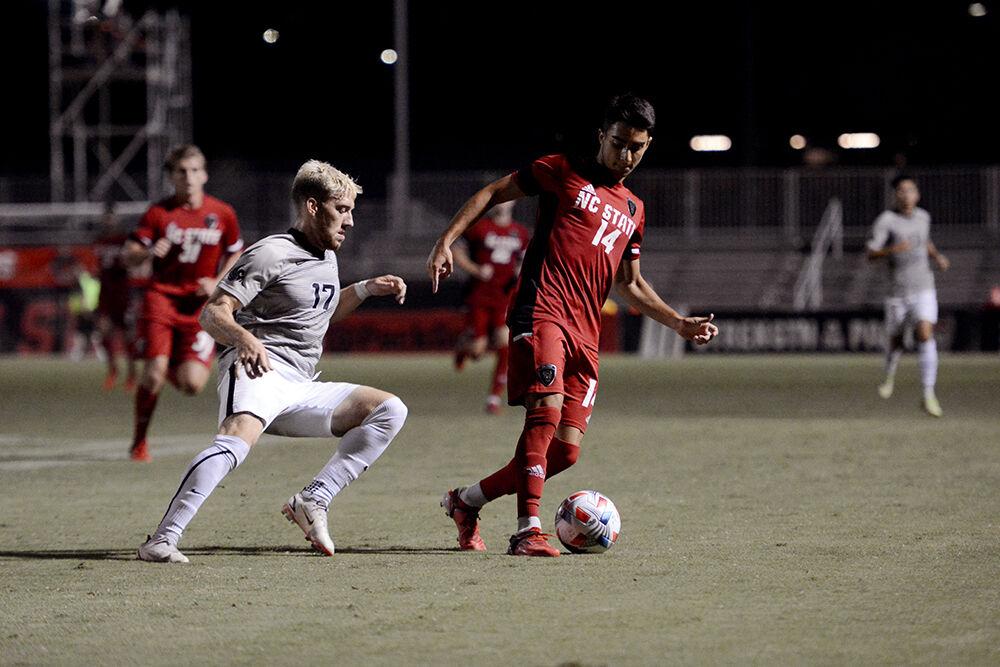Freshman forward Henrique Santos dribbles the ball away from UCF senior midfielder Caleb Franke in the game against UCF on Monday, Sep. 6, 2021 in Dail Soccer Stadium. The Wolfpack beat the Knights 2-1.