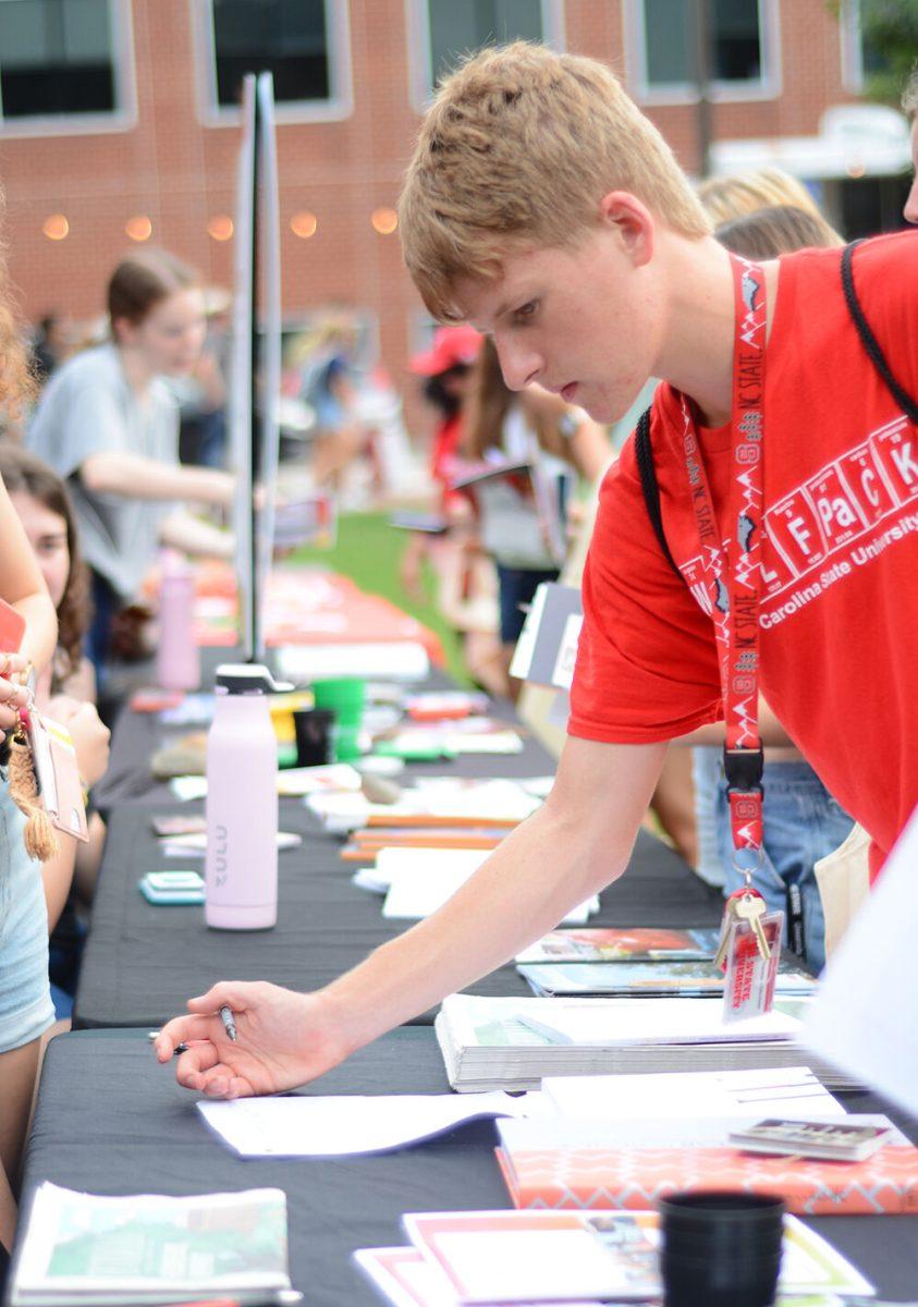 Trent Hidenfelter, a first-year in engineering, writes his name down on the Student Media interest form during the Witherspoon Block Party at Harris Field on Monday, Aug. 22, 2022. Witherspoon's Block Party was an event during Wolfpack Welcome Week to help students get involved with the organizations that are in Witherspoon Student Center.