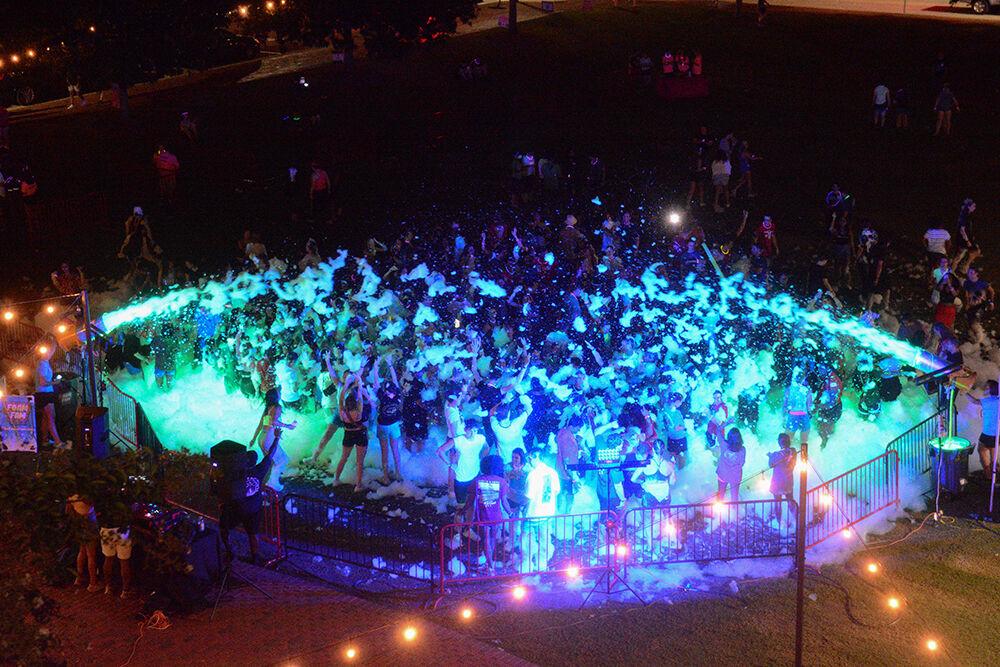 The crowd dances in foam as cannons spray foam overhead during the Foaming Around event at Harris Field on Friday, Aug. 26, 2022.