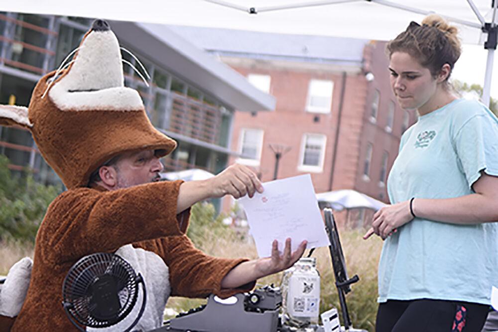 Chris Vitiello, the Poetry Fox, shows finished poem to Enay Jones, second-year studying business administration, at the NC State LIVE block party event at Stafford Commons on Sunday, Sept. 18, 2022. NC State LIVE celebrated its 50th Anniversary with performances from Squonk, Wolfgang A Cappella and Fusion Dance Crew.