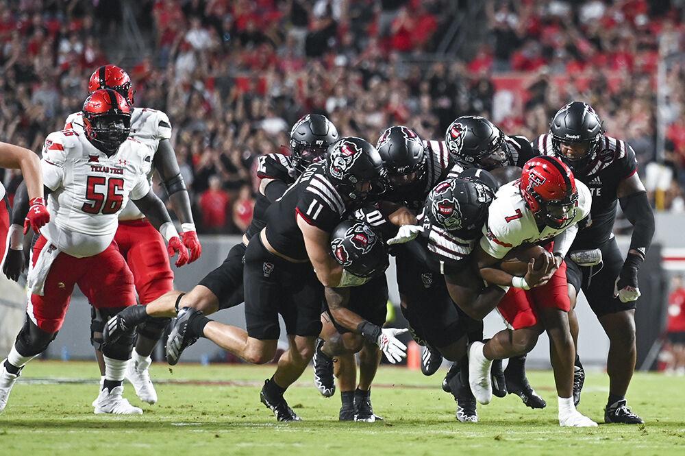 Members of the Wolfpack football team tackle an opposing Texas Tech player during the game at Carter-Finley Stadium on Saturday, Sept. 17, 2022. The Wolfpack beat the Raiders 27-14.