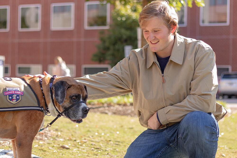 Evans Humphreys, a second-year student studying human biology, pets eight-year-old boxer Milo at the Pause for Paws event at Harris Field on Tuesday, Oct. 18, 2022. Prevention Services organized the Pause for Paws event to help students relax and socialize.