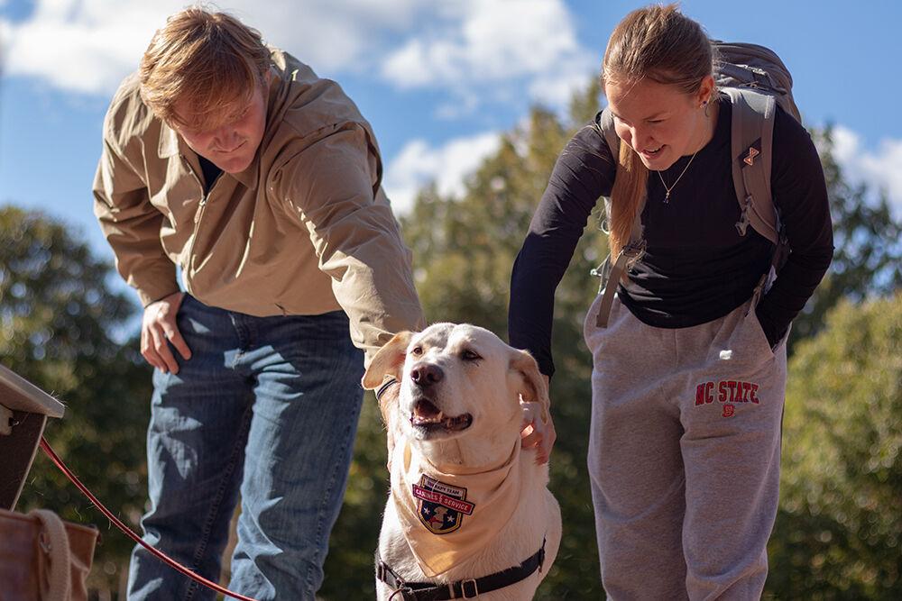 Evans Humphreys (on left), a second-year student studying human biology and Lauren Todd (on right), a second-year studying general biology, pets four-year-old lab mix Magnus the Pause for Paws event at Harris Field on Tuesday, Oct. 18, 2022. Prevention Services organized the Pause for Paws event to help students relax and socialize.