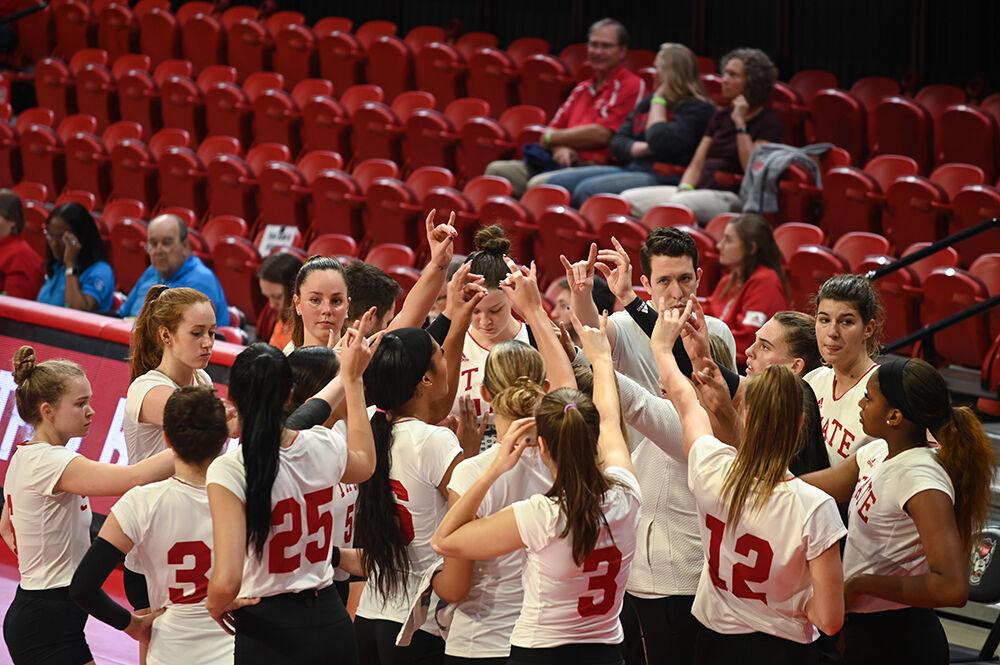 The NC State volleyball team throws up "Wolfies" during the game against Clemson on Friday, Oct. 28, 2022 in Reynolds Coliseum. NC State won the game 3-0 against Clemson.