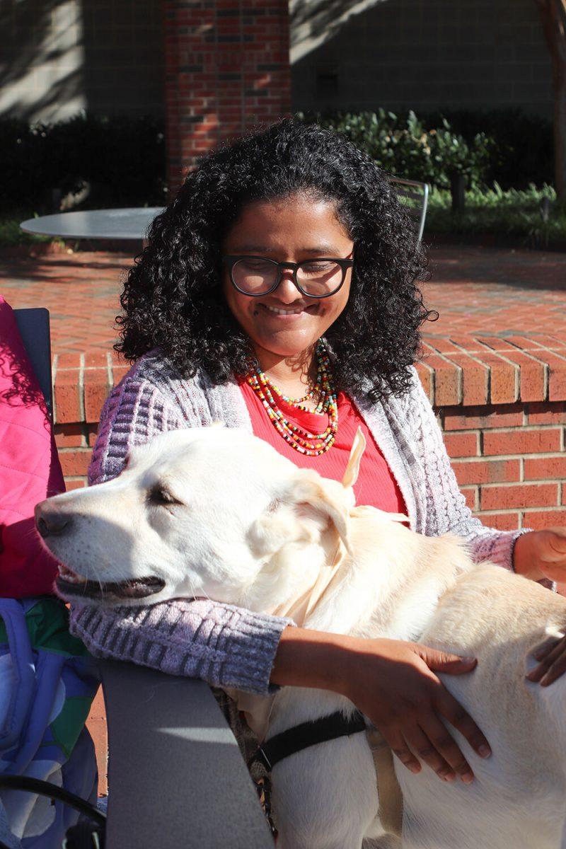 Jime Rodrigues Ribeiro, a graduate student studying forestry, pets Magnus the therapy dog at Pause for Paws at Harris Field on Tuesday, Oct. 18, 2022.