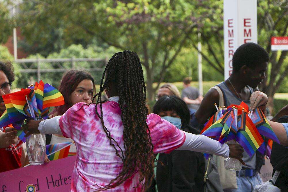 A member of the NC State community passes out pride flags to students during the Pride Walk on Monday, Oct. 3, 2022 around main campus. Members of the NC State community joined the Pride Walk to support one another for National Coming Out Day.