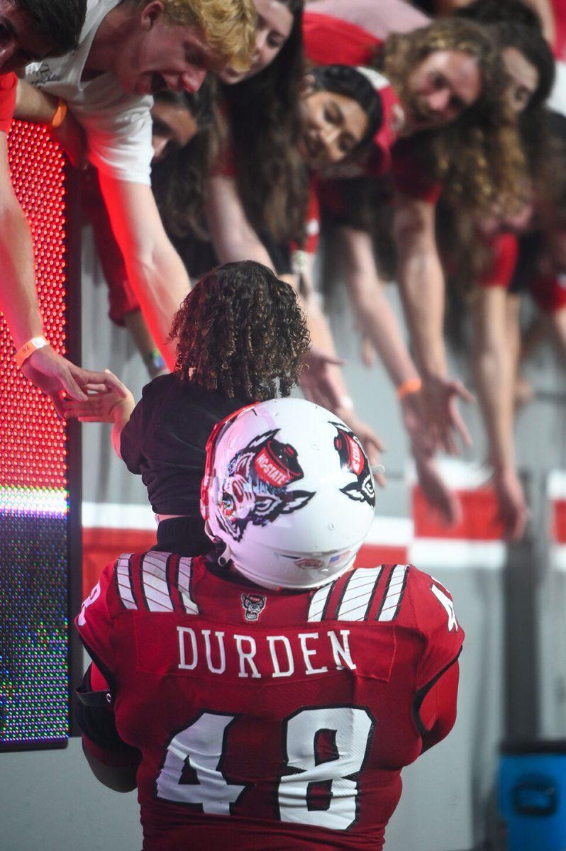 Graduate defensive tackle Corey Durden hoists his child to high five NC State fans after its game over Wake Forest on Saturday, Nov. 5, 2022 at Carter-Finley Stadium. NC State won 30-21.