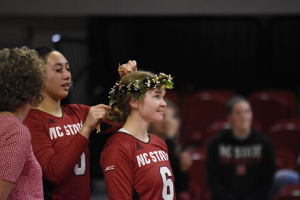 (Left to right) Senior setter Kristen McDaniel ties a flower crown on senior defensive specialist Hannah Wander after the game against Notre Dame on Saturday, Nov. 19, 2022 in Reynolds Coliseum. Wander was one of the graduating seniors honored after the game. NC State beat Notre Dame 3-0.