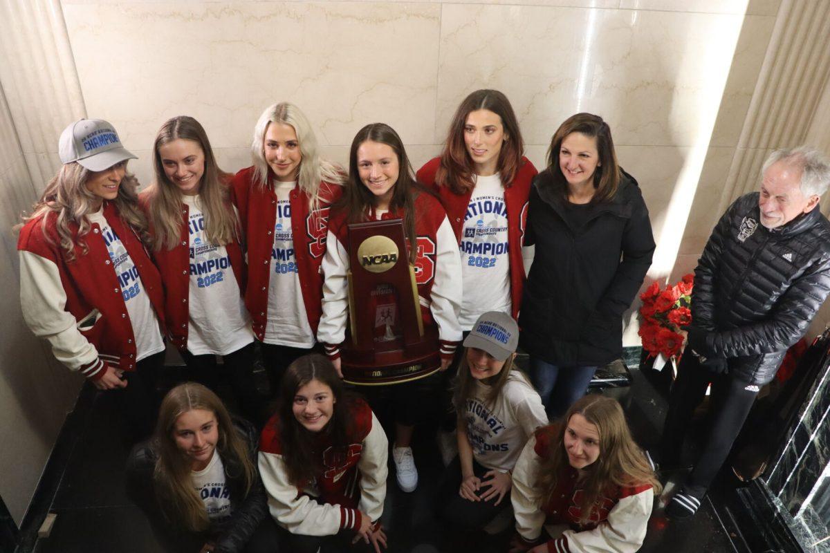 The NC State women's cross country team celebrates its 2022 National Championship with the trophy inside the Memorial Belltower.