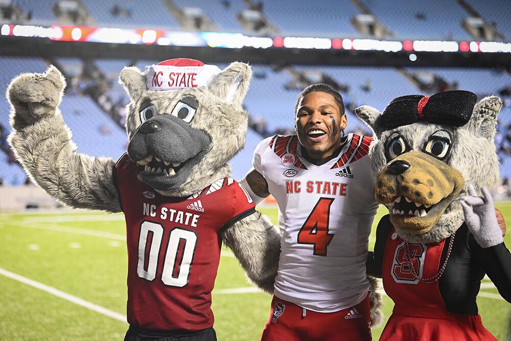 Graduate safety Cyrus Fagan poses with Mr. And Mrs. Wuf after the Wolfpack's last regular season football game against the UNC-Chapel Hill Tar Heels at Kenan Memorial Stadium on Friday, Nov. 25, 2022. The Wolfpack beat the Tar Heels in double overtime 30-27.