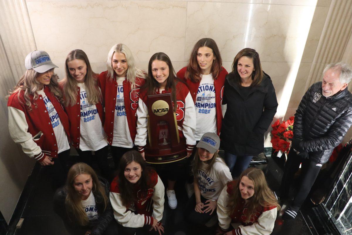 The NC State women's cross country team celebrates its 2022 National Championship with the trophy inside the Memorial Belltower.