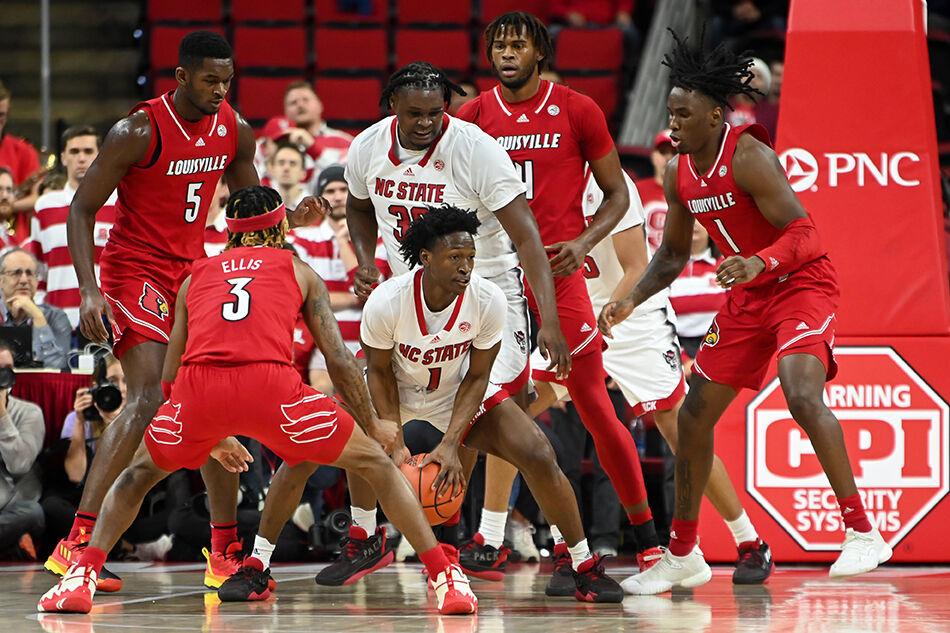 Graduate Guard Jarkel Joiner and graduate forward D.J. Burns Jr. keep the ball away from the defenders during the game against Louisville at PNC Arena on Thursday, Dec. 22, 2022. Joiner made two field goals and one 3-pointer while Burns made four field goals. The Wolfpack beat the Cardinals 76-64.