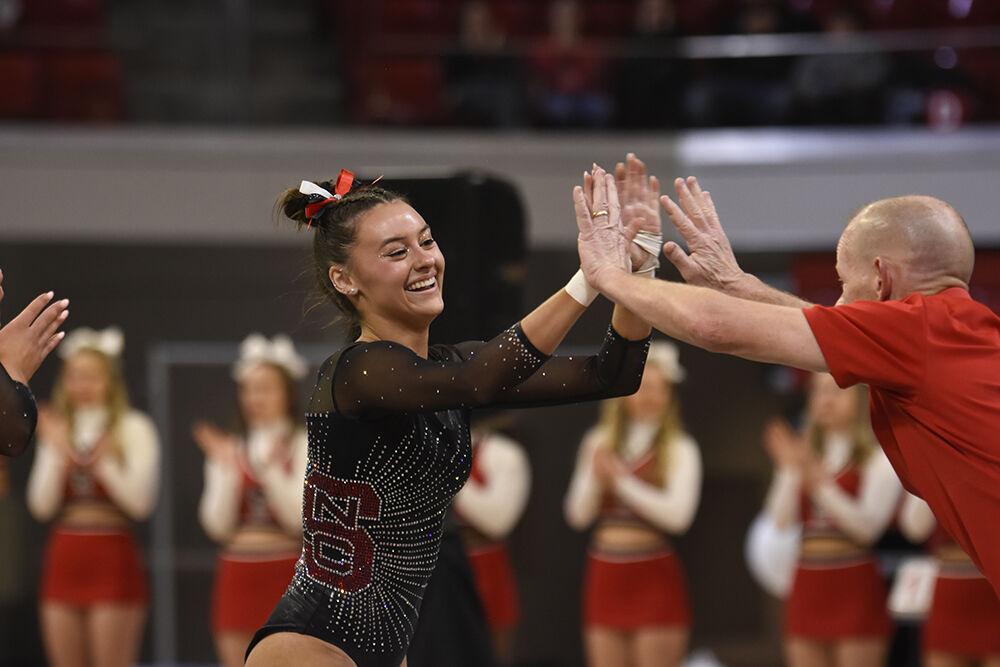 Senior Emily Shepard high-fives assistant coach Philip Ogletree after her floor routine during the match against Michigan State at Reynolds Coliseum on Jan. 14, 2023. Shepard scored 9.90 on her floor routine and 39.45 all around. NC State lost to Michigan State 196.40-196.375.
