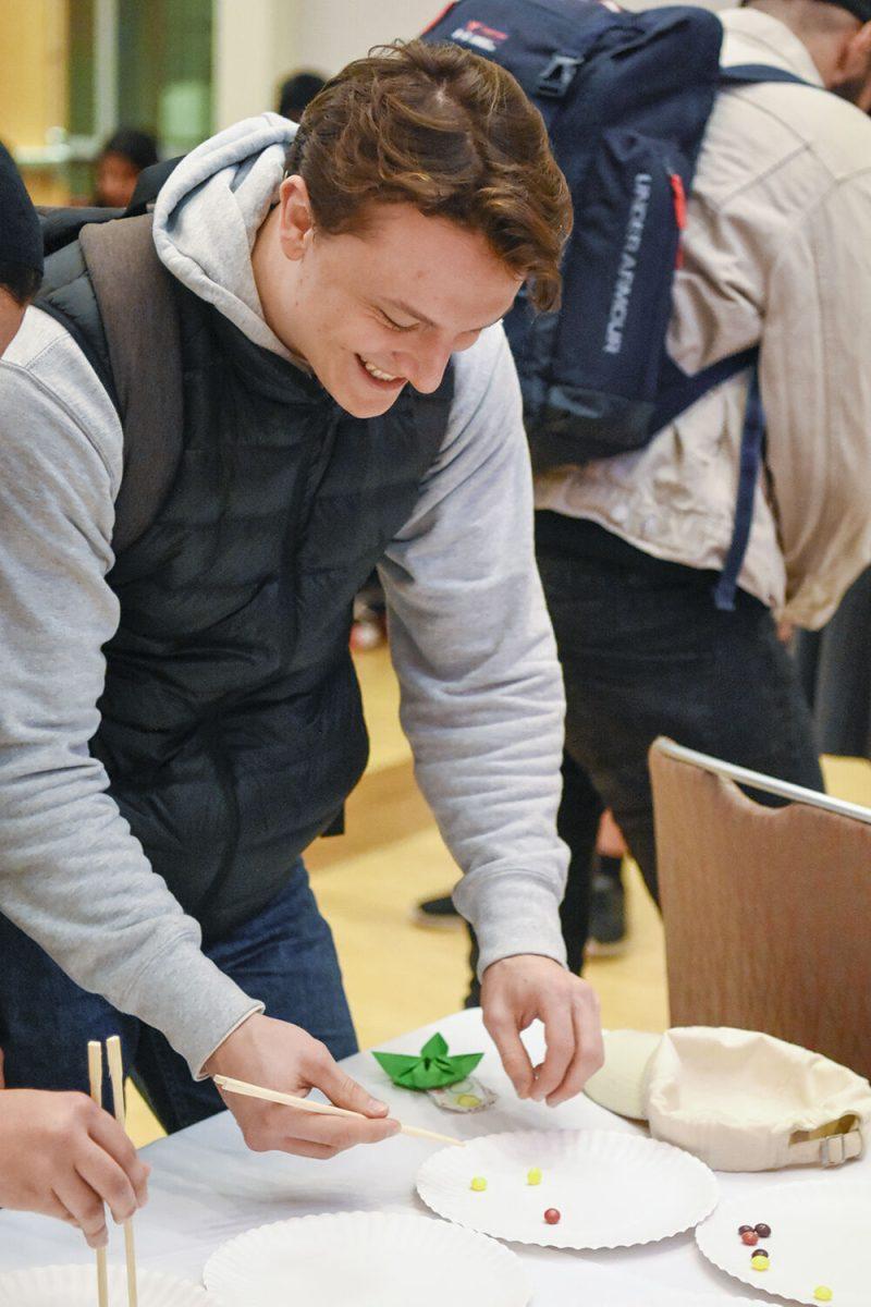 Gwenvael Le Nedellec, a graduate student studying business, attempts to grab Skittles with chopsticks during the Lunar New Year celebration on Jan. 25, 2023, in Talley Student Union. Students celebrated the Chinese New Year in an event that included food, activities, and a performance by KPack.