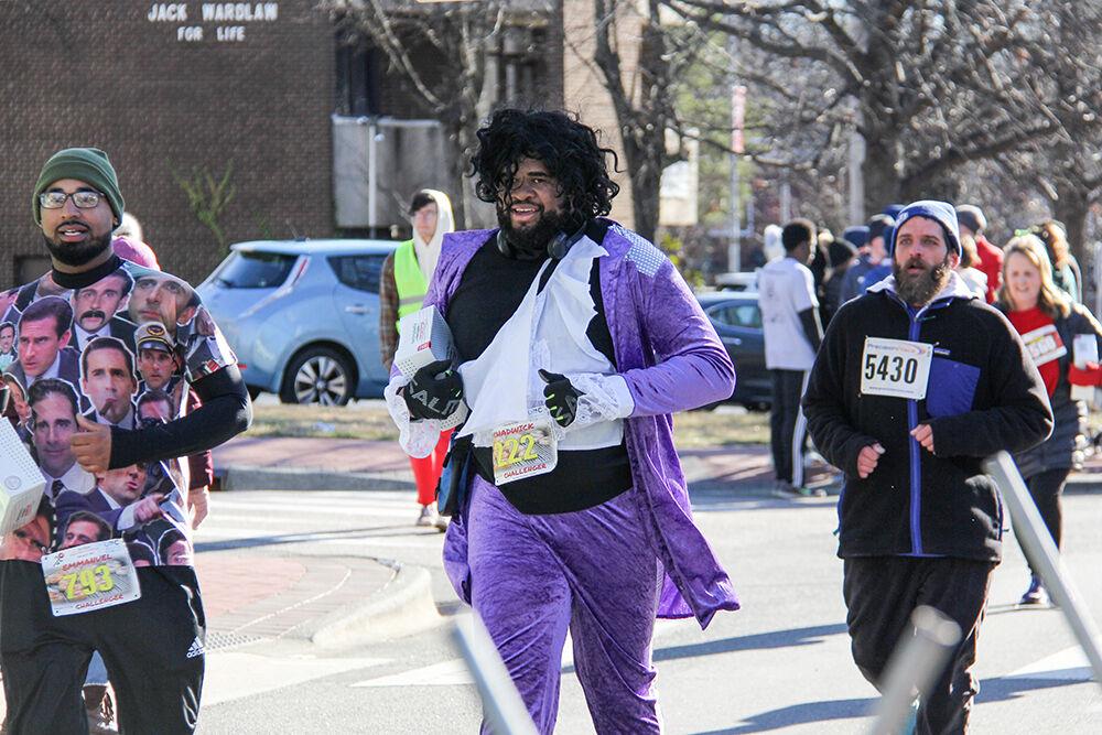 Chadwick Franks crosses the finish line dressed as Prince during the Krispy Kreme Challenge on Hillborough Street on Feb. 4, 2023. The challenge is an annual charity event where participants attempt to run five miles and eat a dozen donuts at the midpoint of the race, all within an hour.