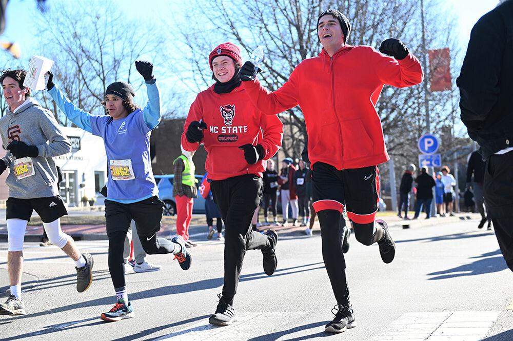 Nate Scofield, Cyrus Jahromi, Walker Bethune and Will Bethume, challenger runners in the 19th annual Krispy Kreme Challenge, cross the finish line on Hillsborough Street during the race on Saturday, Feb. 4, 2023. The race consisted of running five miles while eating a dozen donuts where proceeds benefit the UNC Children's Hospital.