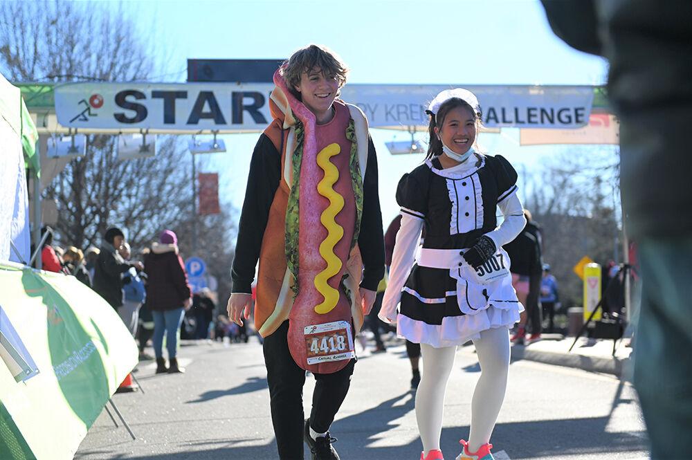 Caitlin Belingon and Mike Molnar, runners in the 19th annual Krispy Kreme Challenge, cross the finish line on Hillsborough Street during the race on Saturday, Feb. 4, 2023. The race consisted of running five miles while eating a dozen donuts where proceeds benefit the UNC Children's Hospital.