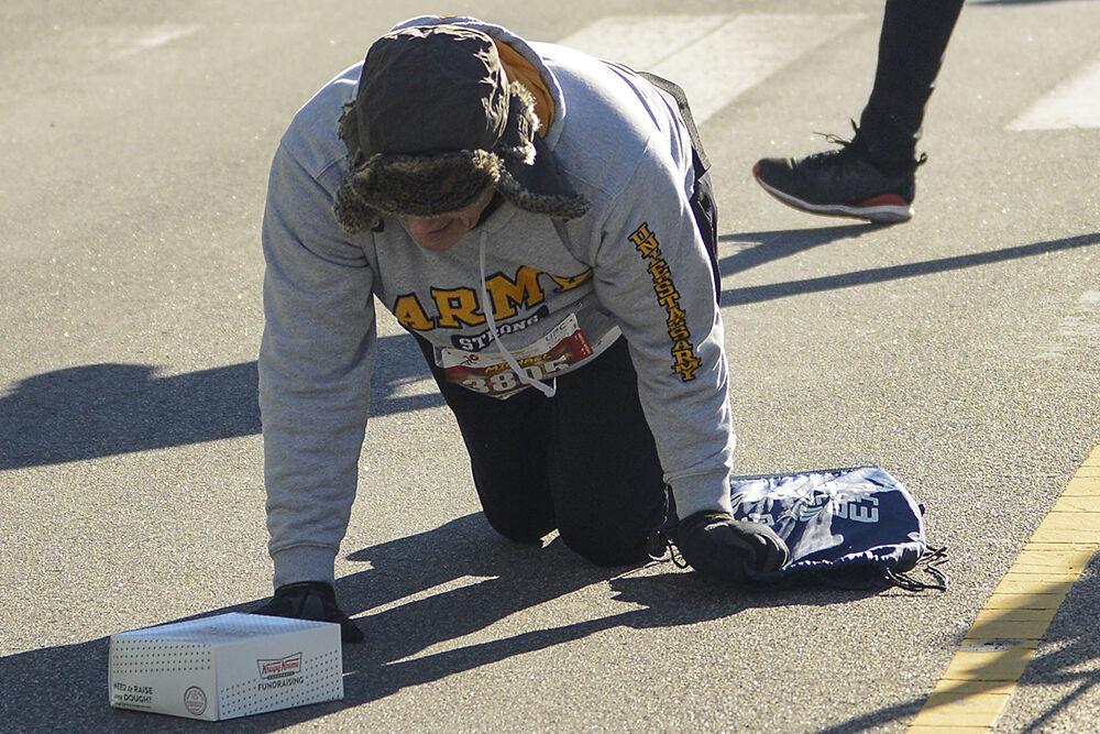 Non-challenger Michael Bawden crawls accross the Krispy Kreme Chellenge finish line on Hillsborough Street on Saturday, Feb. 4 2023. Although most endings weren't as dramatic, many contestants were visibly exhausted when they reached the finish line.