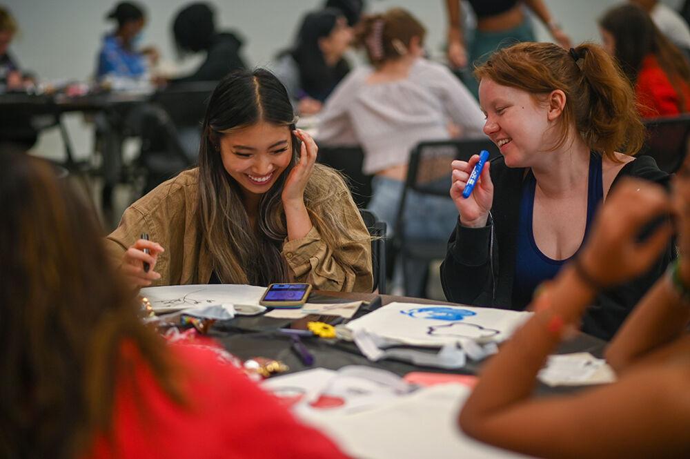 Quin Ho (left), a fourth-year studying business administration and Rebecca Hearn-Phillips, a third-year studying English laugh during the Howl and Chill: Cultivating Self-Love event in Witherspoon Student Center on Tuesday, Feb. 21, 2023. The event allowed students to write positive messages on canvas bags and spend time with friends.
