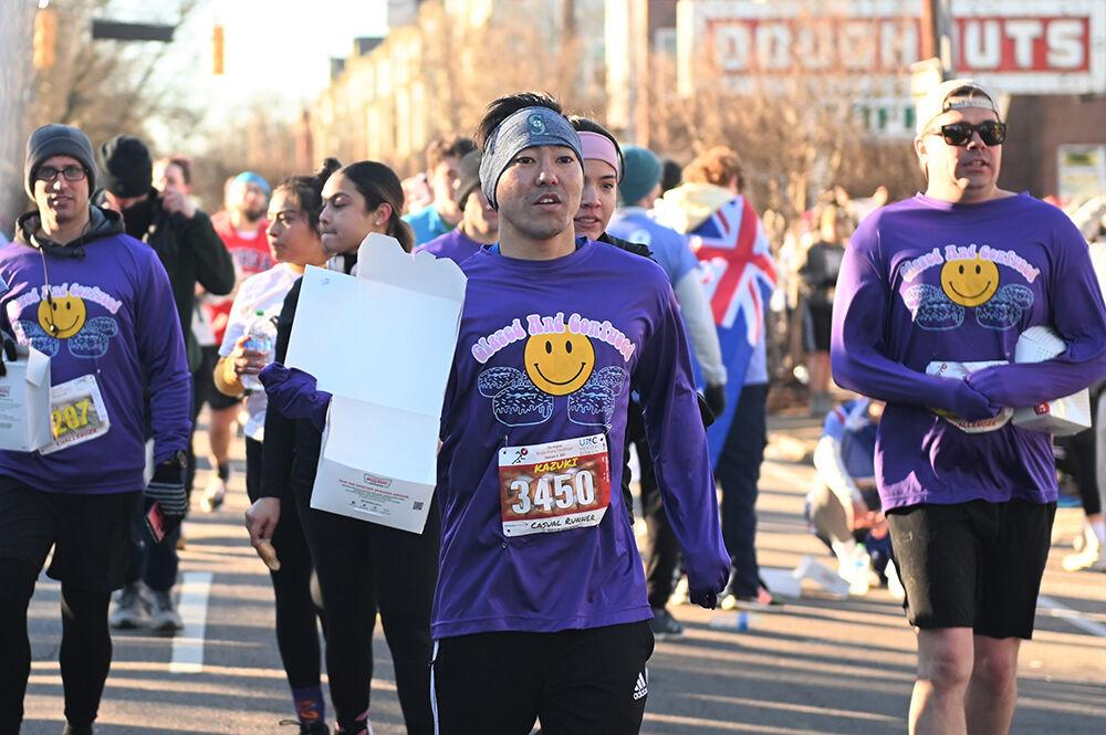 Kazuki Maeshiro, a runner in the 19th annual Krispy Kreme Challenge, runs past the Krispy Kreme in Raleigh, NC during the race showing his empty donut box on Saturday, Feb. 4, 2023. The race consisted of running five miles while eating a dozen donuts where proceeds benefit the UNC Children's Hospital.