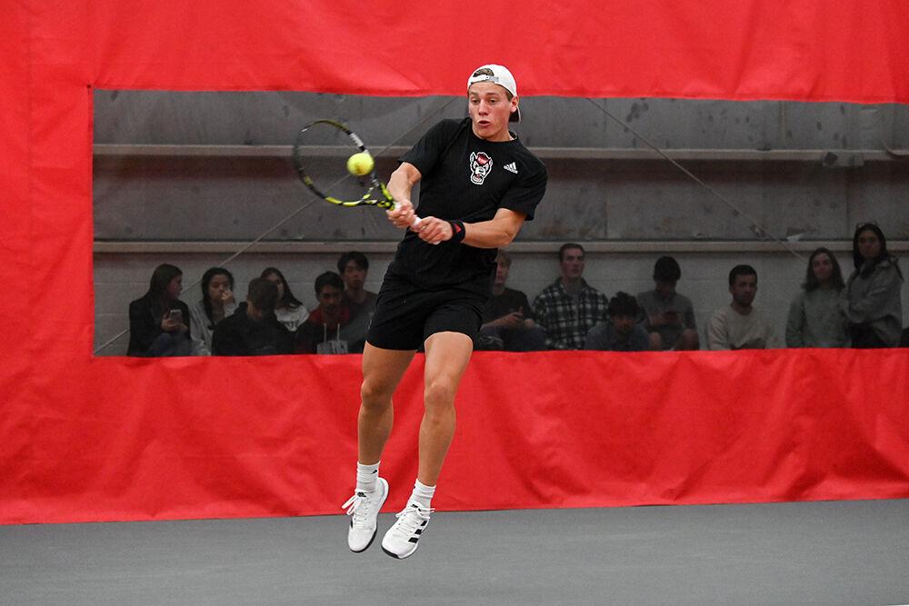 Sophomore Fons Van Sambeek jumps while backhanding the ball during his singles match against Harvard player Valdemar Pape at J.W. Isenhour Tennis Center on Friday, Jan. 20, 2023. Van Sambeek won the singles match 2-0. NC State lost 4-3 to Harvard.