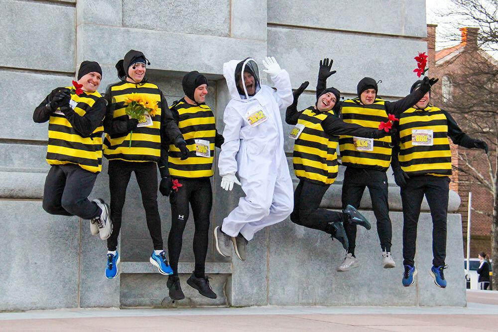 Friends dressed as bees jump for a photo during the Krispy Kreme Challenge on Hillsborough Street on Feb. 4, 2023. The challenge is an annual charity event where participants attempt to run five miles and eat a dozen donuts at the midpoint of the race, all within an hour.